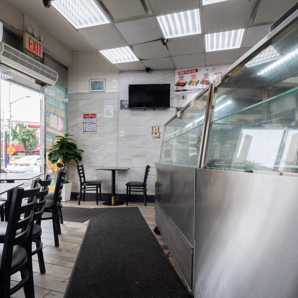Interior of a restaurant with black tables and chairs, a display case, and an exit sign.