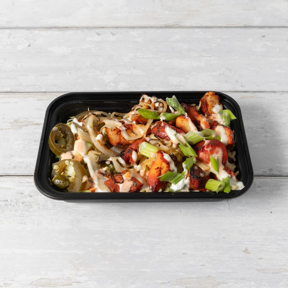 Chicken and rice bowl with onions, jalapeños, and green onions, drizzled with white and red sauces.