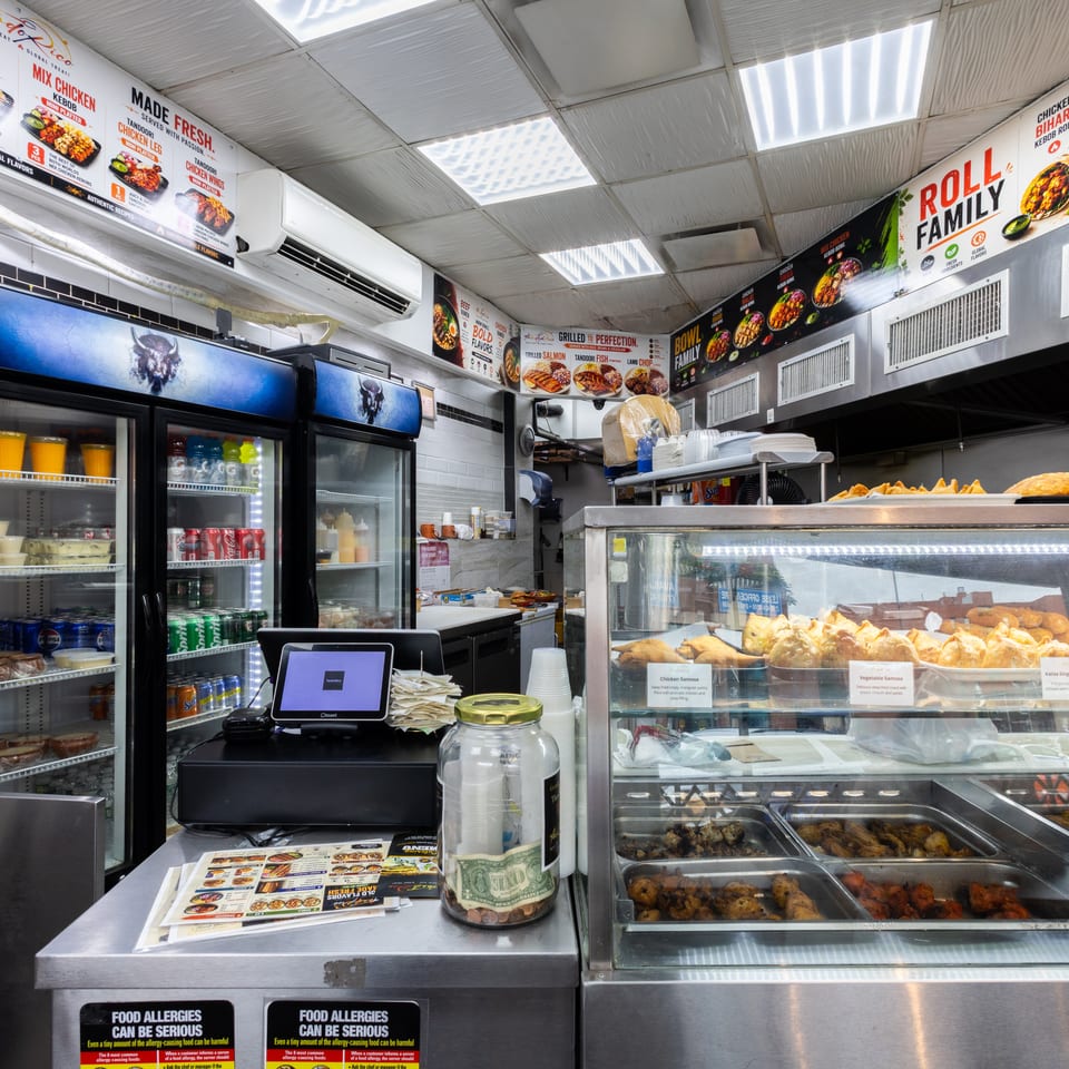 A brightly lit counter inside a restaurant, displaying food in a glass case and menu boards above.