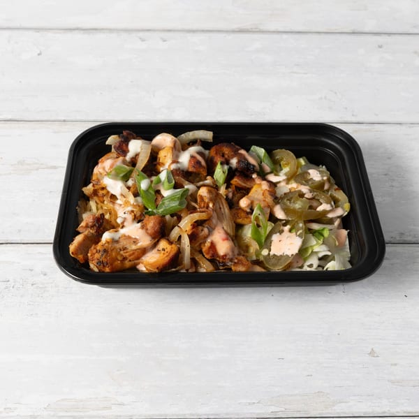 A black takeout container filled with grilled chicken, onions, green onions, and jalapeños, drizzled with sauce.