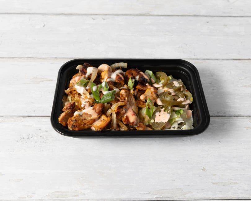 A black takeout container filled with grilled chicken, onions, green onions, and jalapeños, drizzled with sauce.