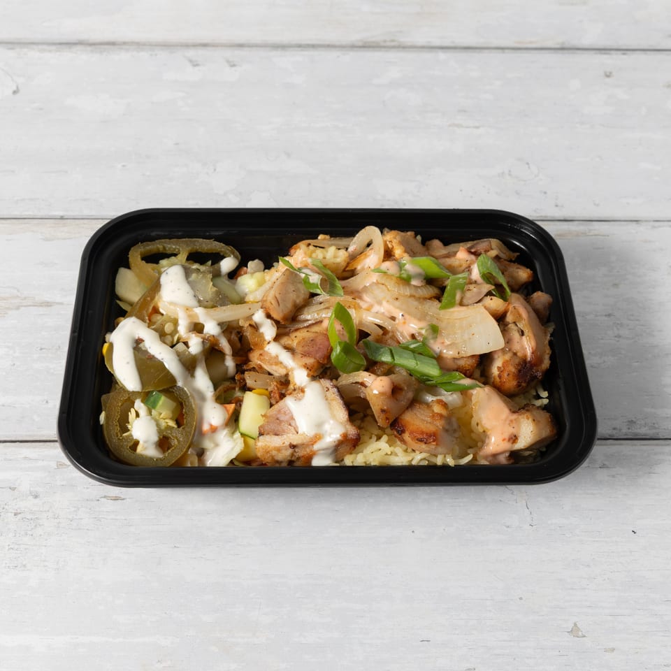 Chicken and rice bowl with jalapeños, onions, and sauces in a black container.